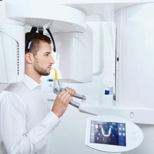 Handsome man doing roentgen at light medical background, portrait, dentist, modern clinic.